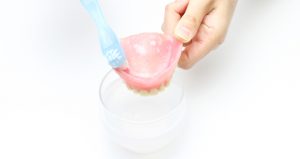 入れ歯をブラシで洗う